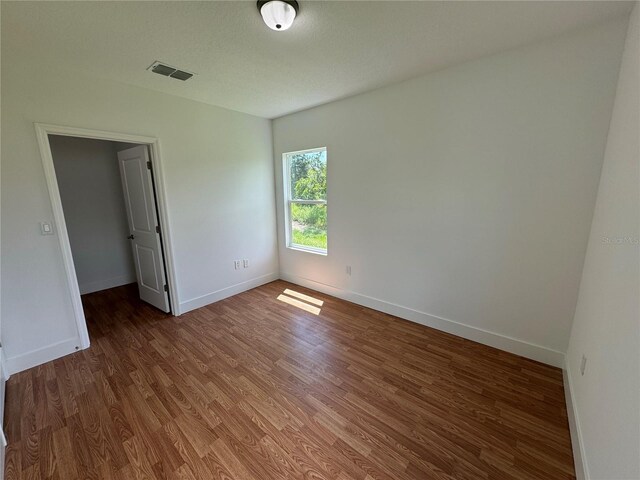 spare room featuring a textured ceiling and dark hardwood / wood-style flooring