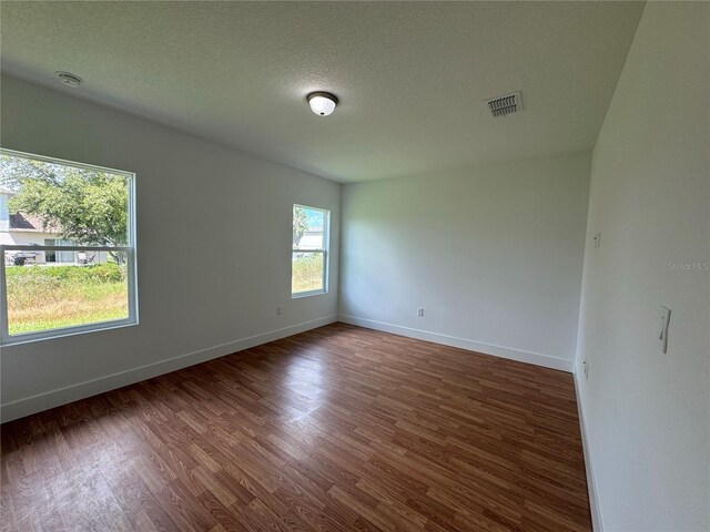 empty room featuring a textured ceiling and dark hardwood / wood-style flooring