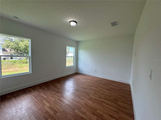 spare room featuring visible vents, wood finished floors, baseboards, and a textured ceiling