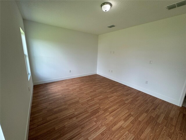 empty room featuring dark hardwood / wood-style floors and a textured ceiling