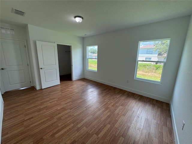 unfurnished bedroom with visible vents, baseboards, wood finished floors, and a spacious closet