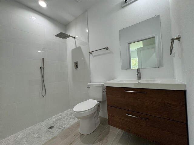 bathroom with tiled shower, toilet, and vanity