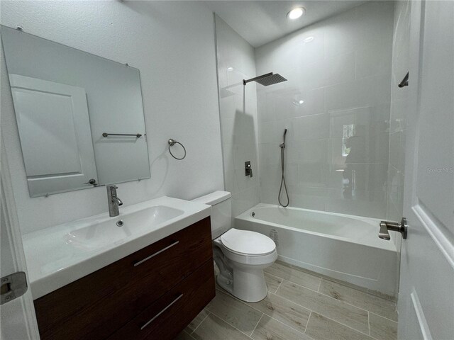 full bathroom featuring toilet, tiled shower / bath combo, and vanity