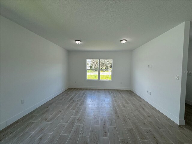 unfurnished room with a textured ceiling and light hardwood / wood-style floors