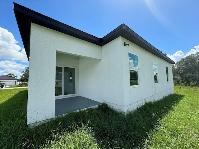 view of side of property featuring stucco siding and a yard