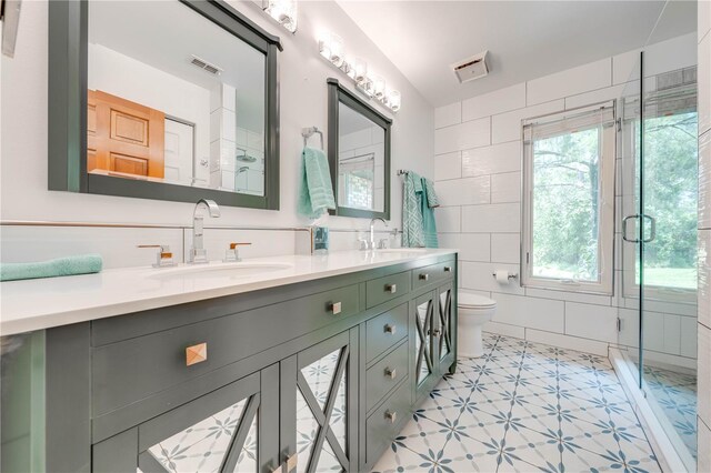 bathroom with toilet, walk in shower, vanity, and tile walls