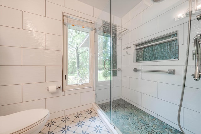 bathroom featuring toilet, an enclosed shower, and tile patterned flooring