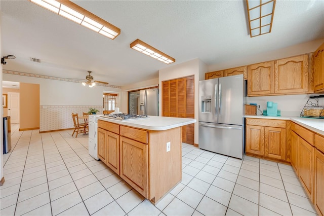 kitchen with ceiling fan, stainless steel appliances, light tile patterned floors, and a kitchen island