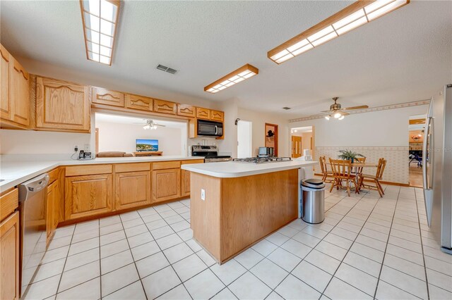 kitchen featuring a textured ceiling, appliances with stainless steel finishes, a center island, and light tile patterned flooring