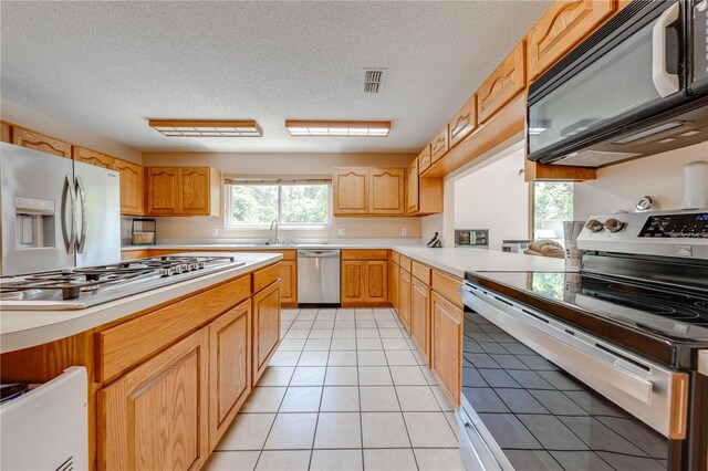 kitchen featuring sink, appliances with stainless steel finishes, a textured ceiling, and light tile patterned floors