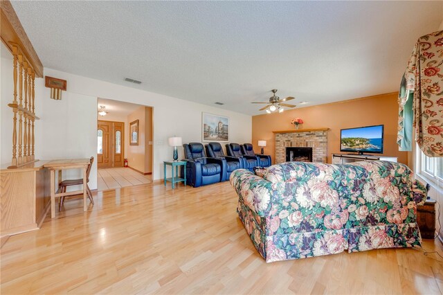 living room with hardwood / wood-style floors, a fireplace, a textured ceiling, and ceiling fan