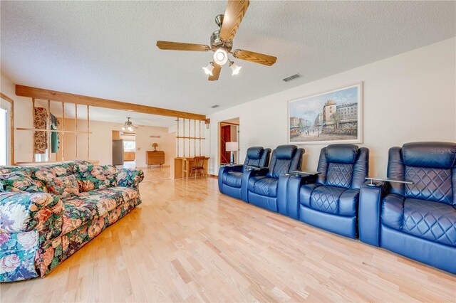 living room with a textured ceiling, wood-type flooring, and ceiling fan