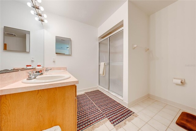 bathroom with a shower with door, vanity, and tile patterned flooring