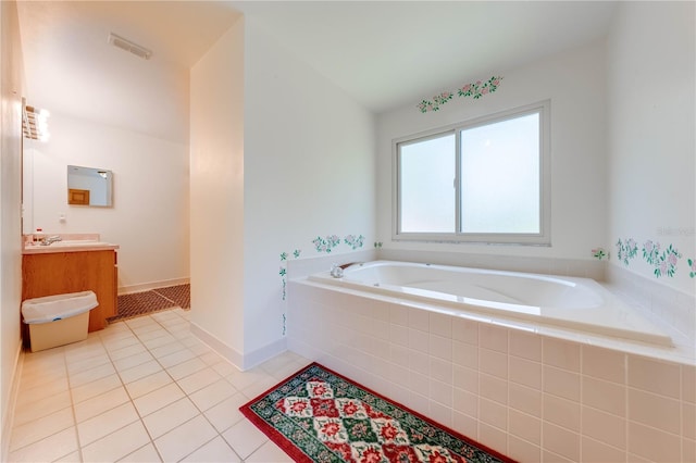 bathroom featuring vanity, a relaxing tiled tub, vaulted ceiling, and tile patterned flooring