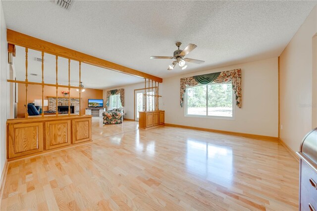 living room featuring light hardwood / wood-style flooring, a textured ceiling, and ceiling fan