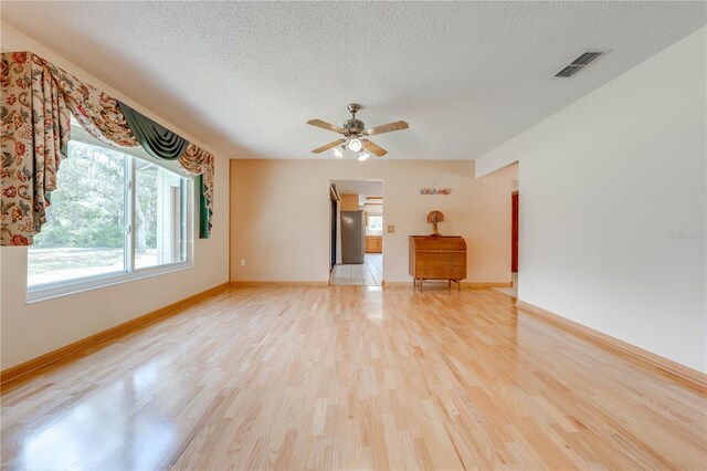 unfurnished living room with a textured ceiling, light wood-type flooring, and ceiling fan