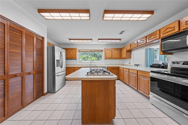 1775 Sundance Dr, Saint Cloud, FL 34771 - kitchen featuring appliances with stainless steel finishes, light countertops, a kitchen island, a textured ceiling, and light tile patterned flooring