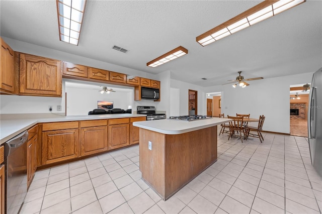 1775 Sundance Dr, Saint Cloud, FL 34771 - kitchen featuring appliances with stainless steel finishes, a ceiling fan, light tile patterned flooring, brown cabinetry, and a center island
