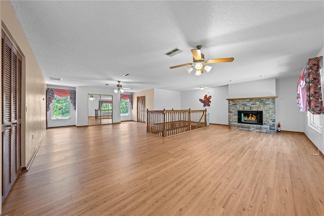 1775 Sundance Dr, Saint Cloud, FL 34771 - unfurnished living room featuring a ceiling fan, light wood finished floors, a textured ceiling, a brick fireplace, and baseboards