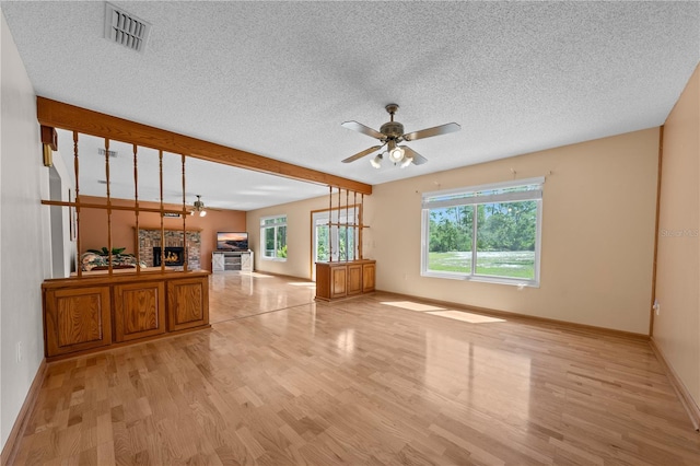 1775 Sundance Dr, Saint Cloud, FL 34771 - unfurnished living room with a ceiling fan, light wood-type flooring, a textured ceiling, a lit fireplace, and baseboards