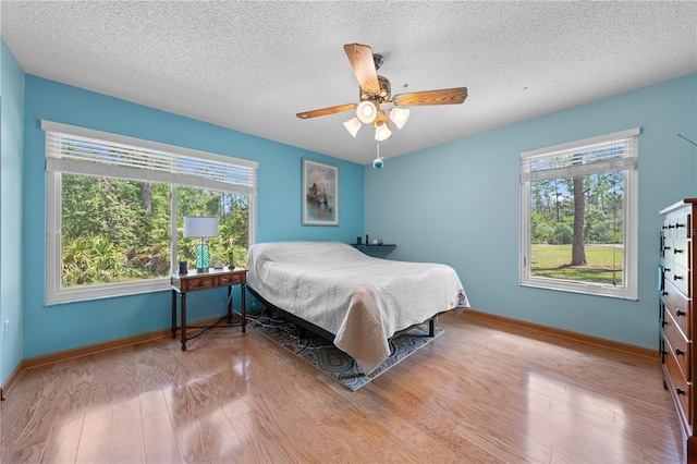1775 Sundance Dr, Saint Cloud, FL 34771 - bedroom with multiple windows, a textured ceiling, baseboards, and wood finished floors