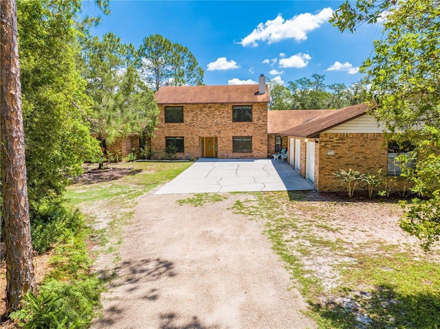 1775 Sundance Dr, Saint Cloud, FL 34771 - back of house featuring brick siding, driveway, and a chimney