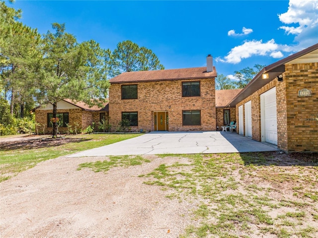 1775 Sundance Dr, Saint Cloud, FL 34771 - back of house with driveway, a chimney, brick siding, and an attached garage