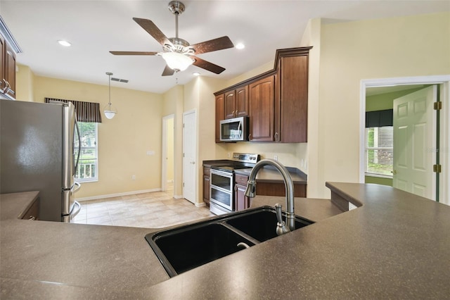 kitchen featuring ceiling fan, stainless steel appliances, light tile patterned floors, and a healthy amount of sunlight