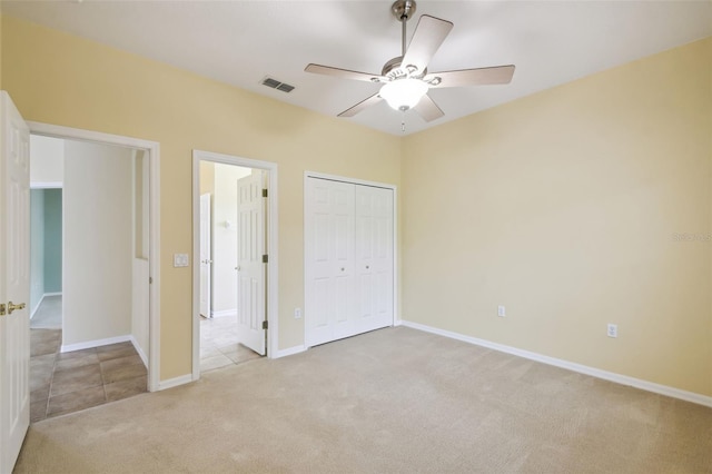 unfurnished bedroom featuring ceiling fan, light colored carpet, and a closet