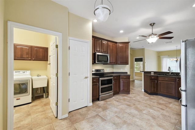 kitchen with pendant lighting, washer / dryer, sink, ceiling fan with notable chandelier, and appliances with stainless steel finishes