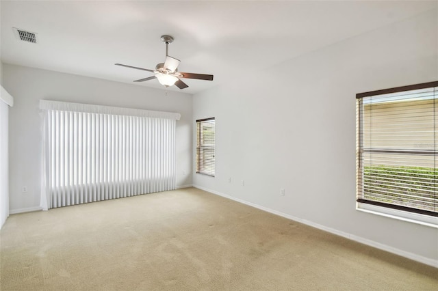 empty room featuring a healthy amount of sunlight, light carpet, and ceiling fan