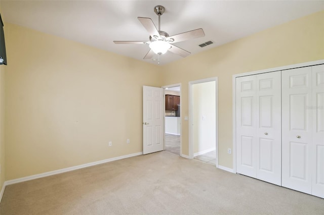 unfurnished bedroom featuring ceiling fan, light colored carpet, and a closet