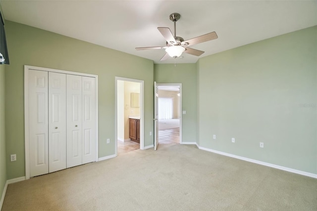 unfurnished bedroom featuring light carpet, a closet, ceiling fan, and ensuite bathroom