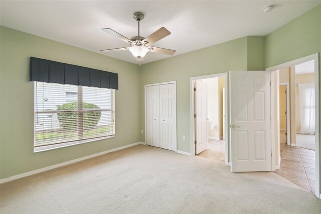 unfurnished bedroom featuring connected bathroom, ceiling fan, light colored carpet, and a closet