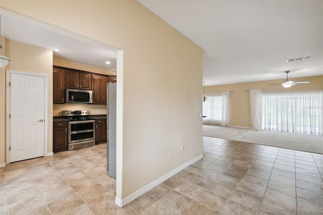 kitchen featuring appliances with stainless steel finishes, dark brown cabinetry, light carpet, and ceiling fan