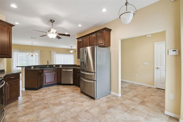 kitchen featuring dark brown cabinetry, pendant lighting, kitchen peninsula, appliances with stainless steel finishes, and ceiling fan with notable chandelier