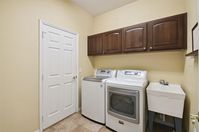 clothes washing area with washer and clothes dryer, light tile patterned floors, cabinets, and sink