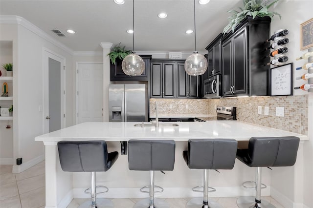 kitchen with a kitchen breakfast bar, appliances with stainless steel finishes, hanging light fixtures, and sink