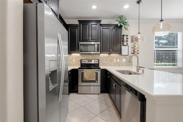 kitchen featuring kitchen peninsula, pendant lighting, stainless steel appliances, crown molding, and sink