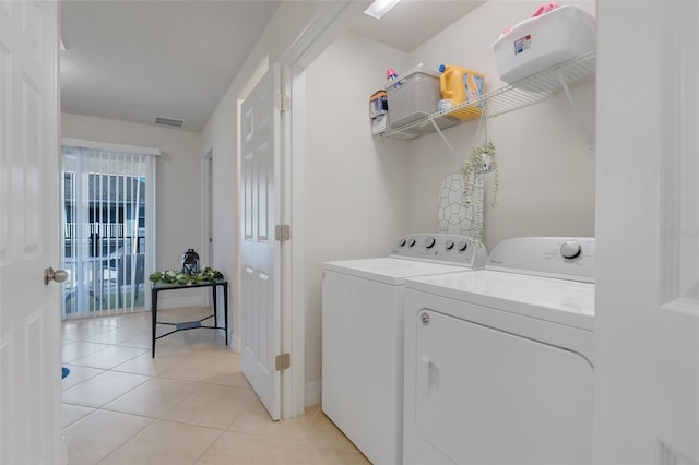 laundry area featuring light tile patterned floors, washing machine and clothes dryer, and plenty of natural light