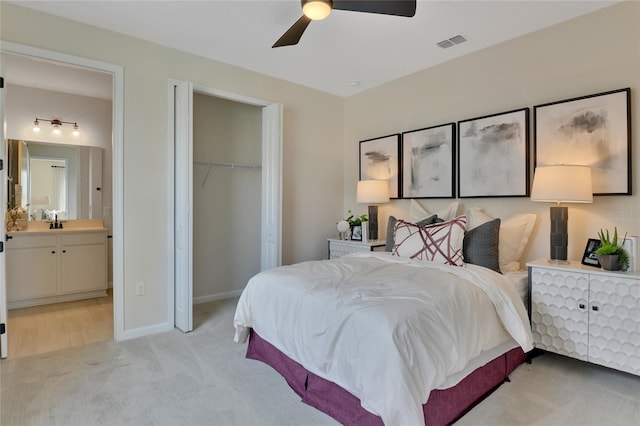 bedroom with a closet, sink, light carpet, ensuite bathroom, and ceiling fan