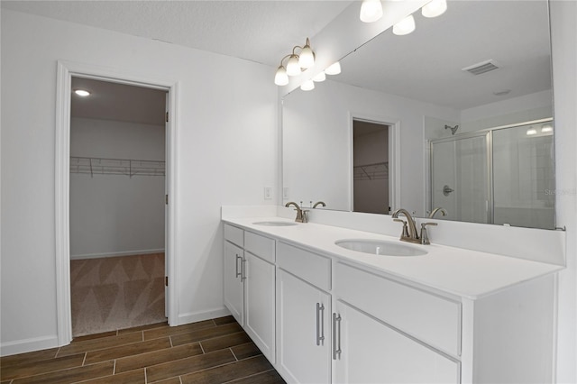 bathroom with a shower with door, vanity, and a textured ceiling