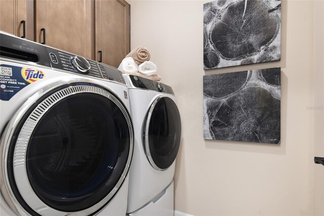 clothes washing area featuring washer and dryer and cabinets