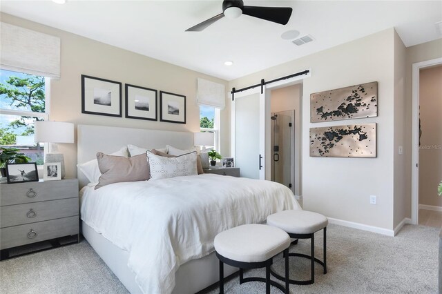 carpeted bedroom featuring a barn door, ceiling fan, and multiple windows