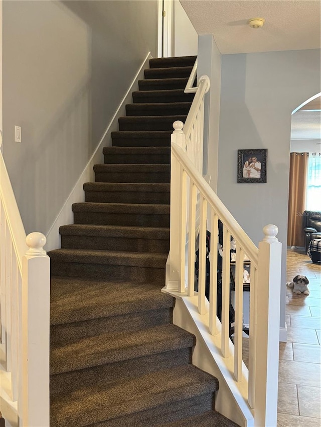 stairs featuring a textured ceiling