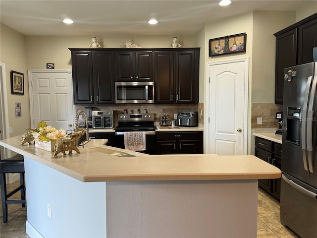 kitchen with a center island with sink, appliances with stainless steel finishes, and tasteful backsplash