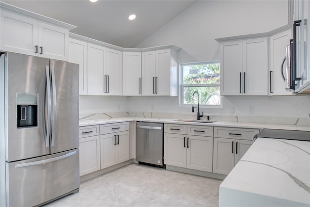 kitchen featuring light stone countertops, light tile patterned floors, stainless steel appliances, sink, and lofted ceiling