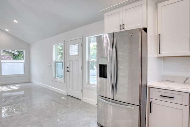 kitchen with white cabinets, vaulted ceiling, light stone counters, and stainless steel refrigerator with ice dispenser