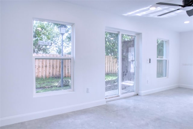 empty room with ceiling fan and a wealth of natural light