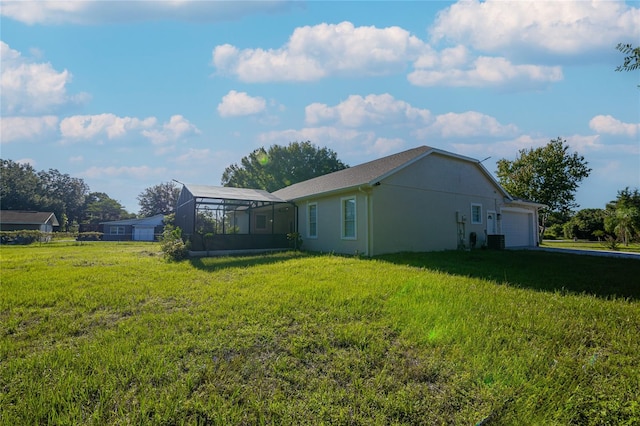 view of yard featuring glass enclosure, a garage, and central AC